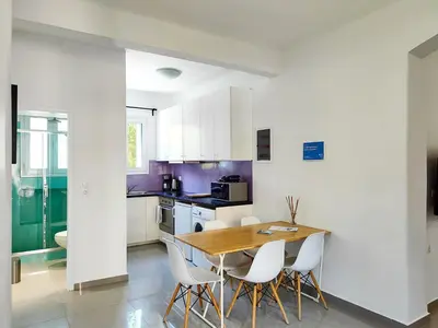 a kitchen with a wooden table and white cabinets at KYMA Apartments - Athens Acropolis 5 in Athens