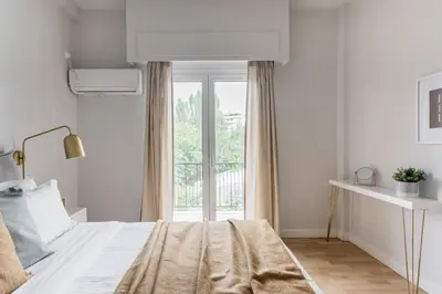 a white bedroom with a bed and a window at Zeus Temple view 2BD Apartment by UPSTREET in Athens