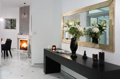 a living room with a table with a mirror and flowers at ALDIS MANSION by K&K in Athens