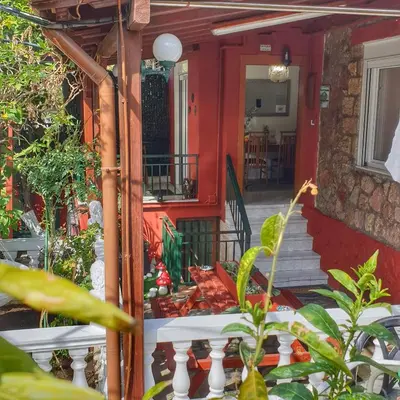 a red house with a white railing and a porch at Stone house under Acropolis in Athens