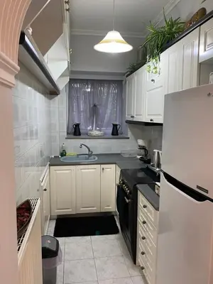 a kitchen with white cabinets and a black refrigerator at Stone house under Acropolis in Athens