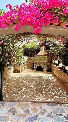 a patio with pink flowers and an arch with a fountain at Stone house under Acropolis in Athens