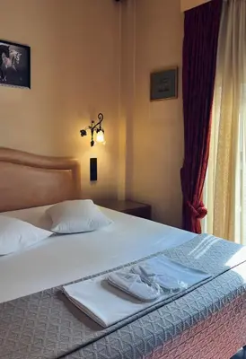 a bed with white sheets and towels on it at Alfa Hotel in Piraeus