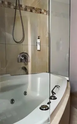a white bath tub with a glass shower door at Alfa Hotel in Piraeus