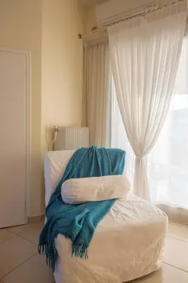 a bed with a blue blanket on it with a window at Acropolis at your fingertips in Athens