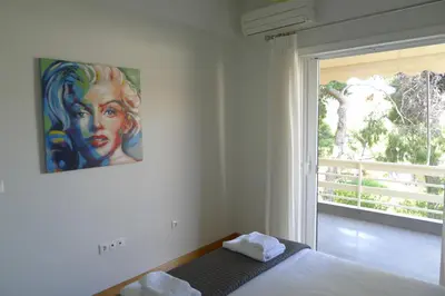 a bedroom with a bed with a painting on the wall at Deluxe Apartment in Vouliagmeni in Athens
