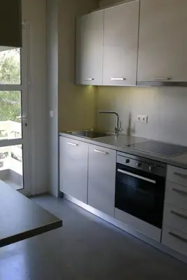 a kitchen with white cabinets and a sink and a stove at Deluxe Apartment in Vouliagmeni in Athens