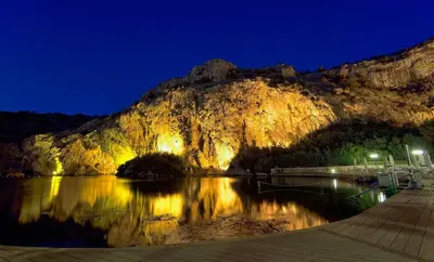 a mountain reflecting in the water at night at Deluxe Apartment in Vouliagmeni in Athens