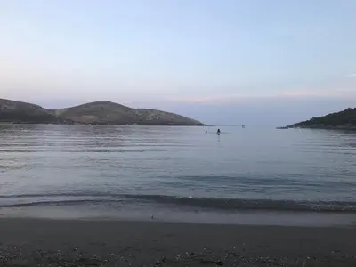 a body of water with a beach and two islands at Surfers' Cottage in Anavissos