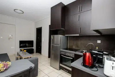 a kitchen with stainless steel appliances and a living room at Apartment & Parking 100m Kerameikos Metro in Athens