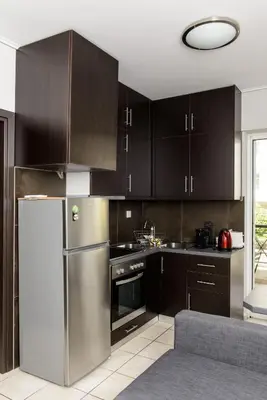 a kitchen with brown cabinets and a stainless steel refrigerator at Apartment & Parking 100m Kerameikos Metro in Athens