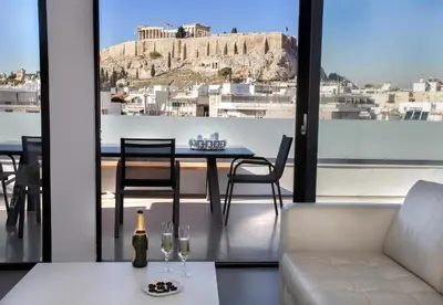 a living room with a table and chairs and a view ofhens at Luxury Penthouse touching the Acropolis by GHH in Athens