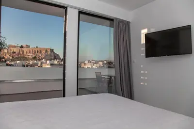 a bedroom with a bed and a flat screen tv at Luxury Penthouse touching the Acropolis by GHH in Athens