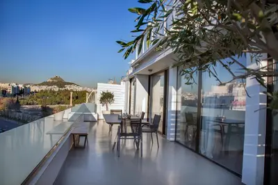 a balcony with tables and chairs on a building at Luxury Penthouse touching the Acropolis by GHH in Athens