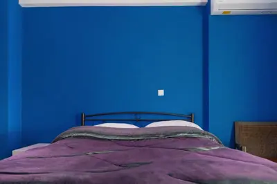 a blue bedroom with a bed with a purple blanket at Cosy Relaxing Flat 60'' from Metro Station in Athens