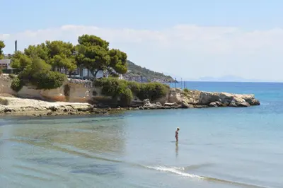a person standing in the water on a beach at Acqua Marina - Άκουα Μαρίνα in Agia Marina Aegina