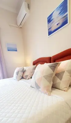 a bedroom with a bed with white sheets and pillows at Acqua Marina - Άκουα Μαρίνα in Agia Marina Aegina