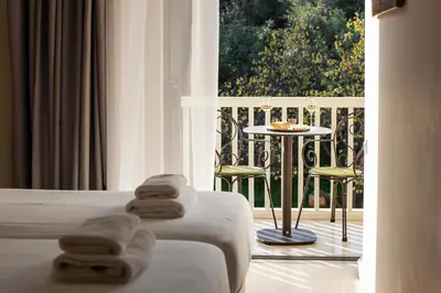 a room with two beds and a balcony with a table and chairs at Acropolis View Hotel in Athens
