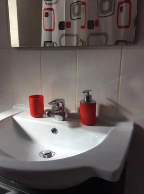 a bathroom sink with two red cups on it at Sunny apartment in Athens