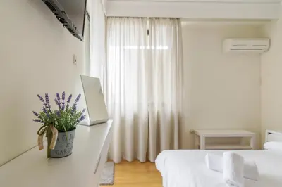 a white bedroom with a bed and a laptop on a desk at Acropolis View apartment 120sqm in Athens