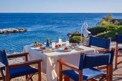 a table with food and the ocean in the background at Grand Resort Lagonissi in Lagonissi