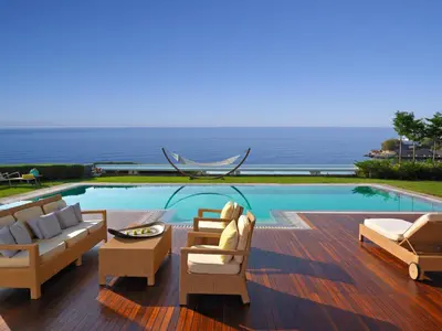 a swimming pool with lounge chairs and a table at Grand Resort Lagonissi in Lagonissi
