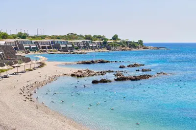 a beach with a bunch of people in the water at Grand Resort Lagonissi in Lagonissi