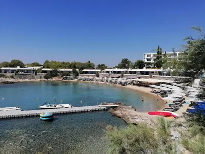 a beach with umbrellas and boats in the water at Grand Resort Lagonissi in Lagonissi