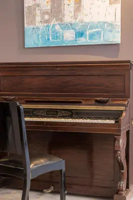 a piano with a chair in front of a painting at Art Suites Athens in Athens