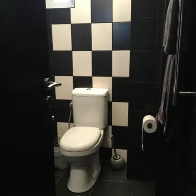 a bathroom with a toilet and a black and white tile wall at Athens Edition 2.0 in Athens