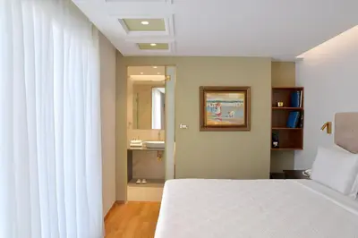 a bedroom with a white bed and a bathroom at Acropolian Spirit Boutique Hotel in Athens