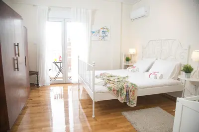 a bedroom with a white bed and a wooden floor at Magnificent luxury retrostyle flat Acropolis view in Athens