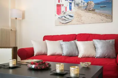 a red couch in a living room with a table at Magnificent luxury retrostyle flat Acropolis view in Athens