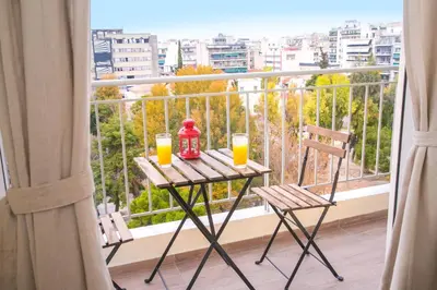 a balcony with a table and two glasses of orange juice at Magnificent luxury retrostyle flat Acropolis view in Athens