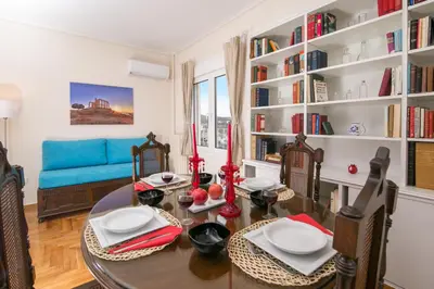 a dining room with a table and a blue couch at Magnificent luxury retrostyle flat Acropolis view in Athens