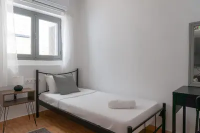 a white bedroom with a bed with a window at Dioskouros Hostel in Athens