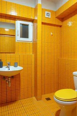 a yellow bathroom with a toilet and a sink at Dioskouros Hostel in Athens