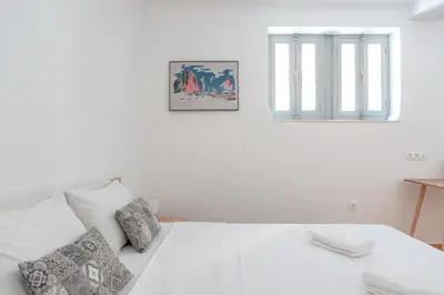 a white bed with two pillows and a window at Dioskouros Hostel in Athens