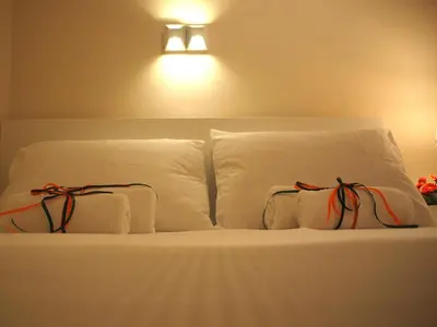 a bed with white pillows and a light on the wall at Cosy Flat Posh Quartier Kolonaki in Athens