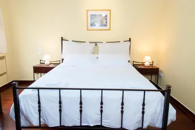 a bedroom with a bed with white sheets and two lamps at Stephany Apartment in Athens