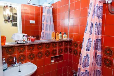 a red tiled bathroom with a sink and a mirror at Stephany Apartment in Athens