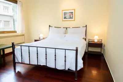 a bedroom with a bed with white sheets and a window at Stephany Apartment in Athens