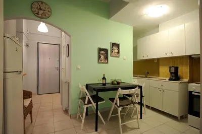 a kitchen with a table and chairs and a clock on the wall at Luxury flat in Kolonaki, 3’ Metro in Athens