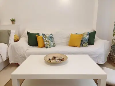 a white living room with a white couch with colorful pillows at Kolonaki Elegant apartment in Athens