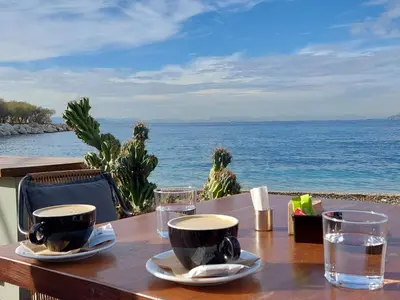 a wooden table with two cups and glasses on the ocean at Krystal Apartment 