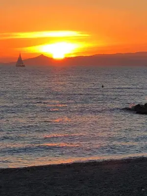 a sunset on the beach with a sailboat in the ocean at Krystal Apartment 