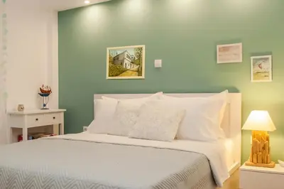 a bedroom with a white bed and a green wall at Acropolis Quiet Apartment in Athens