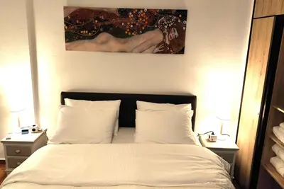 a bedroom with a bed with white sheets and a painting at Ulysses Apartments Acropolis in Athens