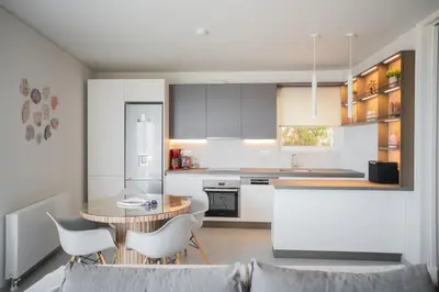 a kitchen with white cabinets and a table and chairs at El Mar Seaview Penthouse 2 BDR, 7 min from beach in Lagonissi