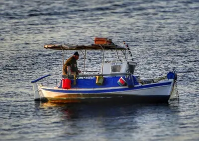 a man in a blue boat in the water at Seaview apartment in Piraeus